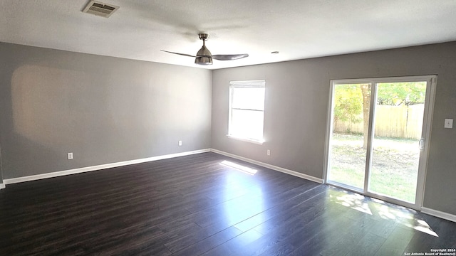 spare room with a healthy amount of sunlight, dark wood-type flooring, and ceiling fan