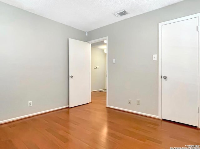 empty room featuring a textured ceiling and hardwood / wood-style floors