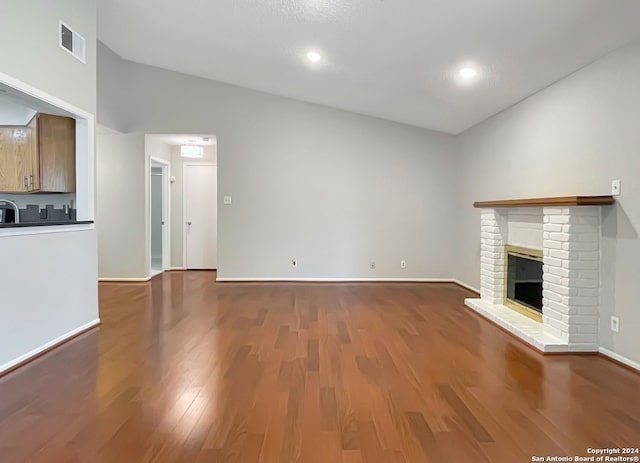 unfurnished living room with dark hardwood / wood-style flooring, high vaulted ceiling, and a brick fireplace