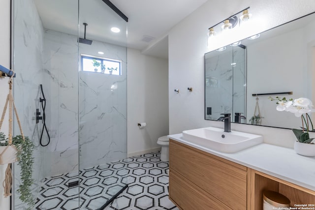 bathroom featuring a tile shower, vanity, and toilet