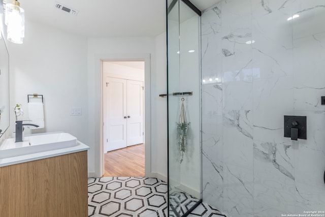 bathroom with wood-type flooring, vanity, and tiled shower