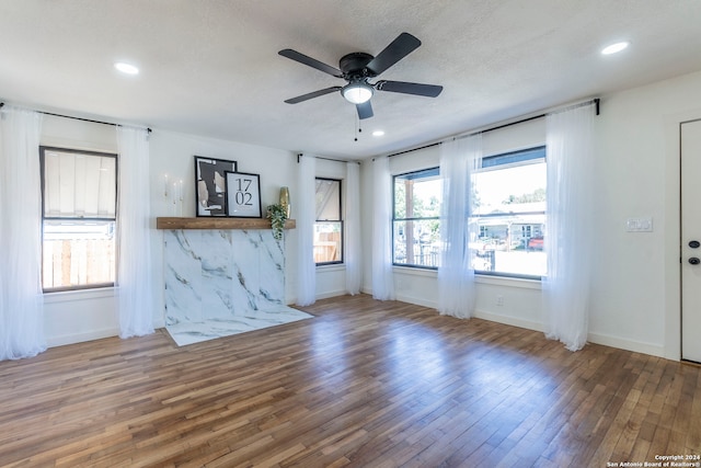 unfurnished living room with a textured ceiling, hardwood / wood-style floors, and ceiling fan