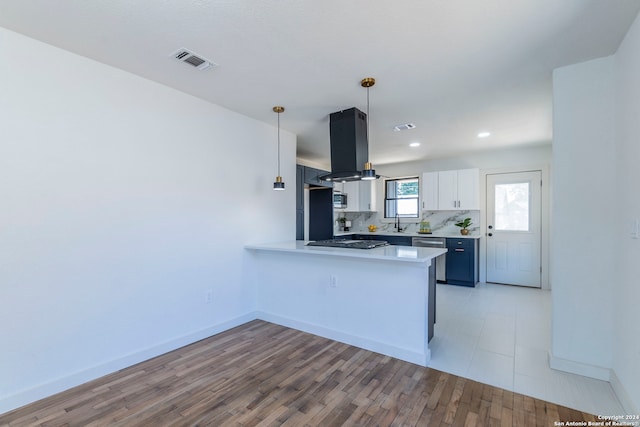 kitchen featuring hanging light fixtures, light hardwood / wood-style floors, white cabinets, kitchen peninsula, and island exhaust hood