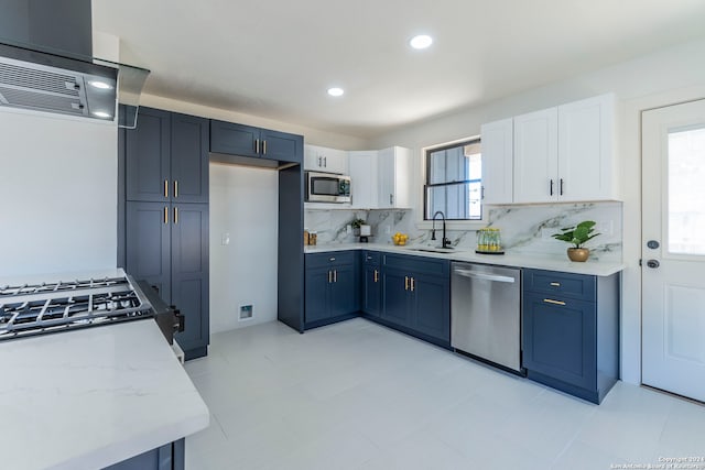 kitchen featuring light stone counters, white cabinets, backsplash, stainless steel appliances, and sink