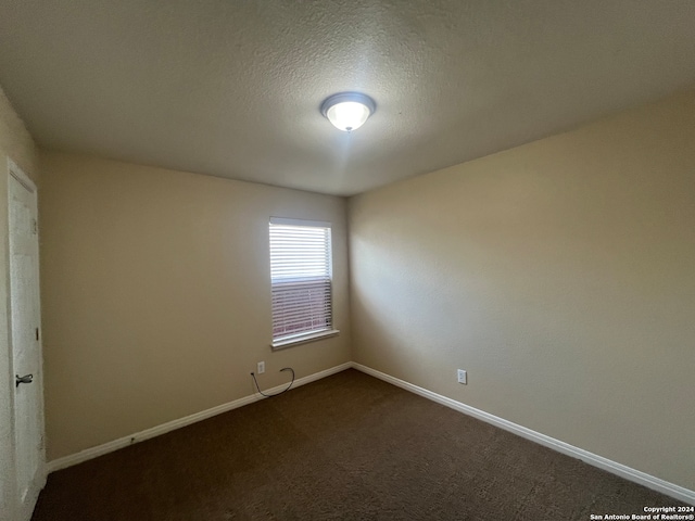 empty room featuring a textured ceiling and dark colored carpet