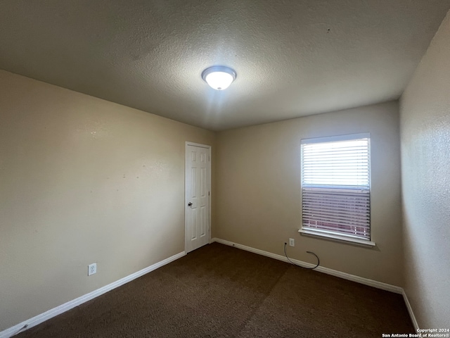 carpeted empty room featuring a textured ceiling