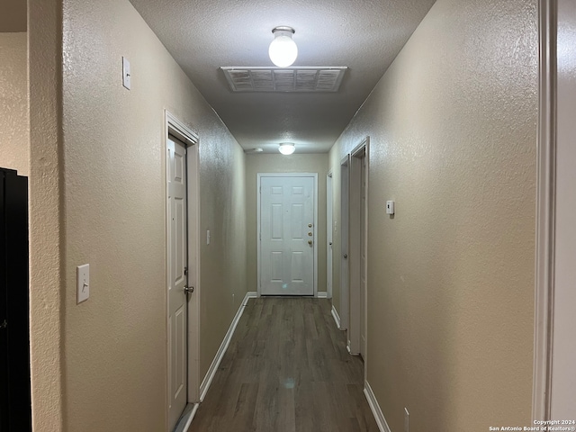 hall with a textured ceiling and dark hardwood / wood-style floors