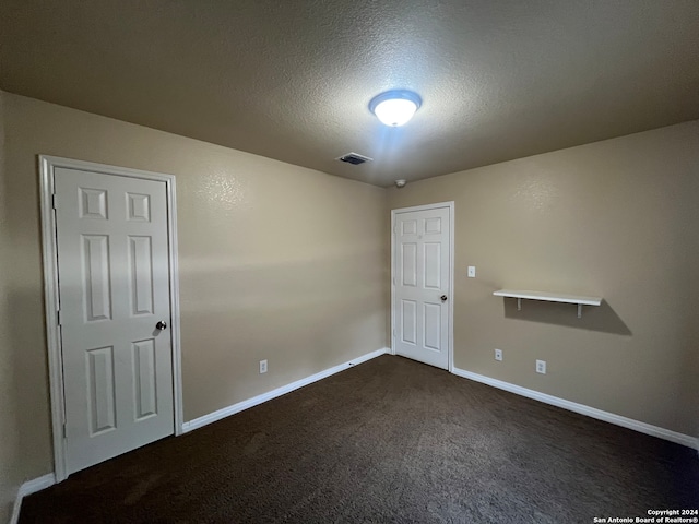 unfurnished room featuring dark carpet and a textured ceiling