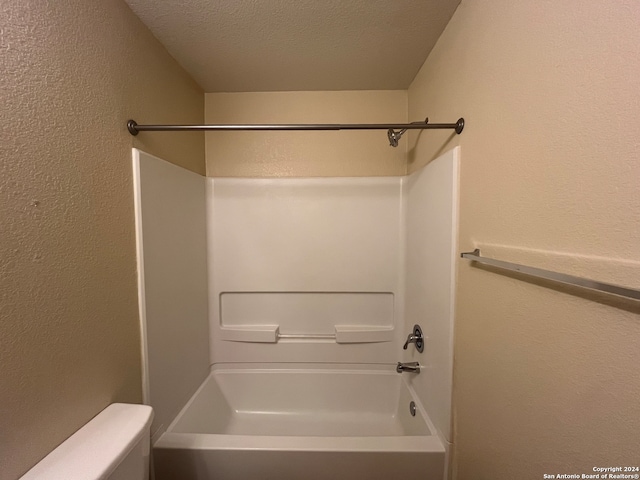 bathroom featuring  shower combination, a textured ceiling, and toilet