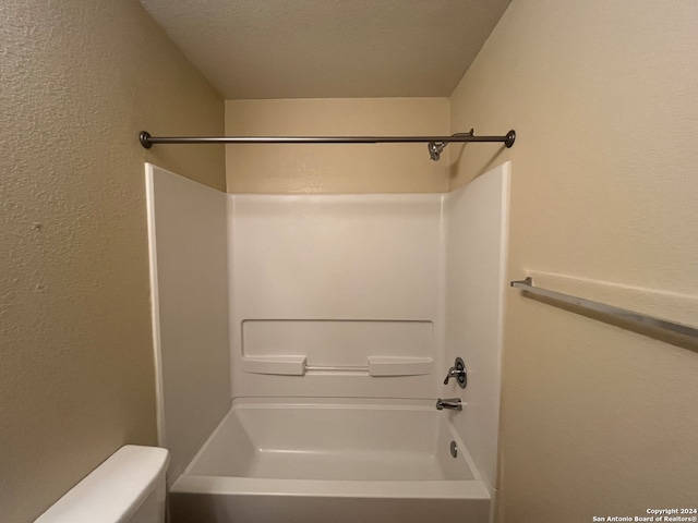 bathroom featuring a textured ceiling,  shower combination, and toilet