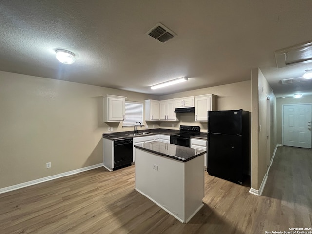 kitchen featuring white cabinets, black appliances, a center island, light hardwood / wood-style flooring, and sink