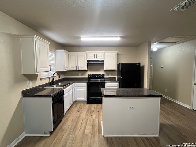 kitchen with sink, a kitchen island, white cabinetry, black appliances, and light wood-type flooring