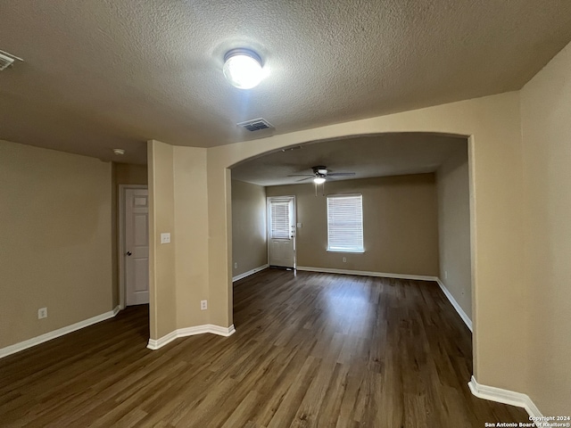 empty room with ceiling fan, dark wood-type flooring, and a textured ceiling