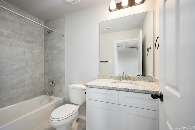 full bathroom with tiled shower / bath, vanity, and toilet