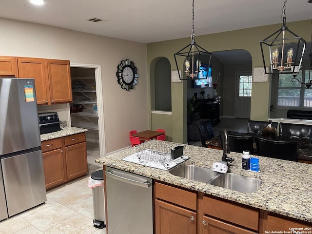 kitchen with stainless steel appliances, light tile patterned floors, decorative light fixtures, and sink