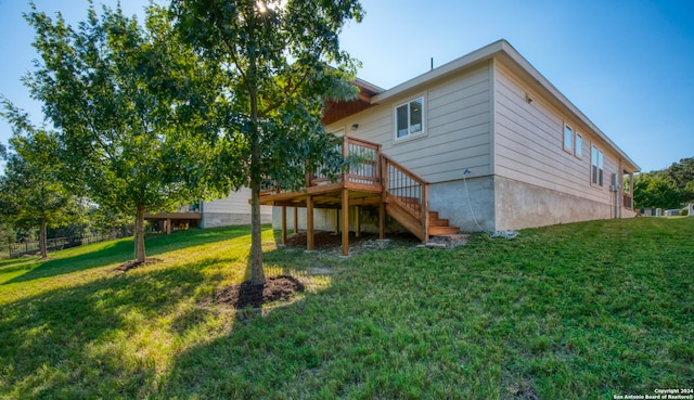 rear view of house with a lawn and a wooden deck