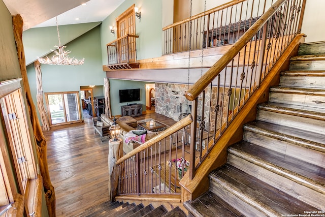 stairway featuring high vaulted ceiling, a chandelier, and hardwood / wood-style floors