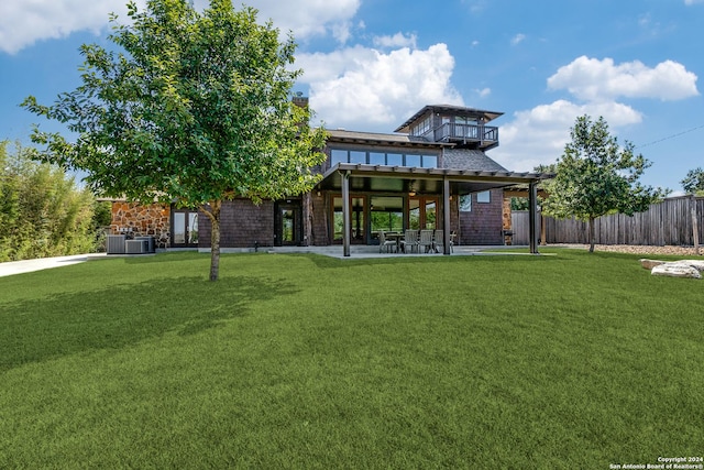 rear view of house featuring central AC unit, a chimney, fence, a yard, and a patio
