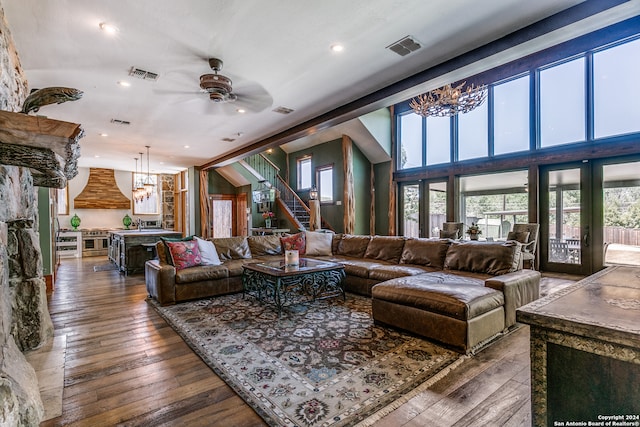 living room with a stone fireplace, ceiling fan with notable chandelier, dark hardwood / wood-style floors, and high vaulted ceiling