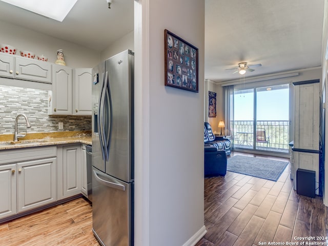 kitchen with ceiling fan, stainless steel fridge, sink, white cabinetry, and light hardwood / wood-style floors