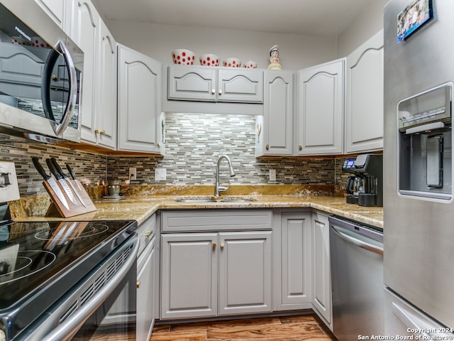 kitchen with sink, white cabinets, backsplash, appliances with stainless steel finishes, and light stone countertops