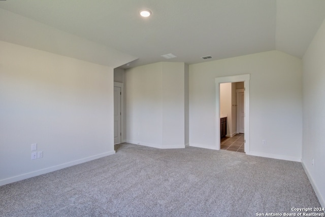 carpeted empty room featuring vaulted ceiling