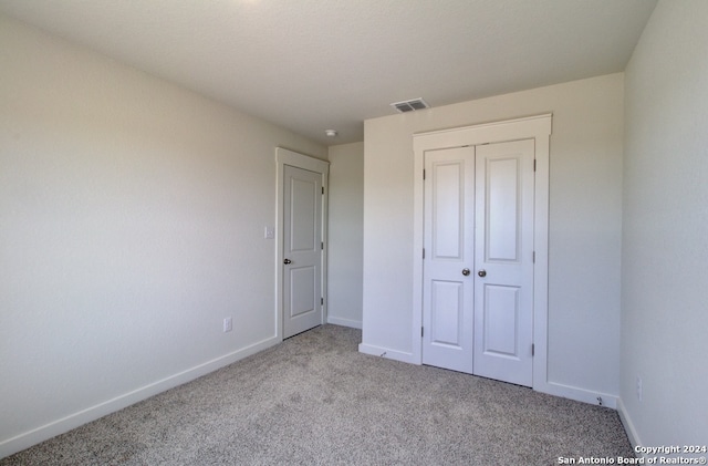 unfurnished bedroom featuring light colored carpet and a closet