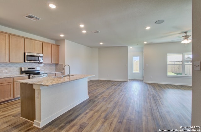 kitchen featuring appliances with stainless steel finishes, dark wood-type flooring, an island with sink, light brown cabinetry, and ceiling fan