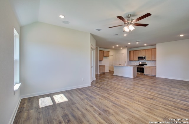 unfurnished living room with light wood-type flooring, vaulted ceiling, and ceiling fan