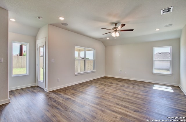 empty room featuring lofted ceiling, ceiling fan, dark hardwood / wood-style floors, and a healthy amount of sunlight