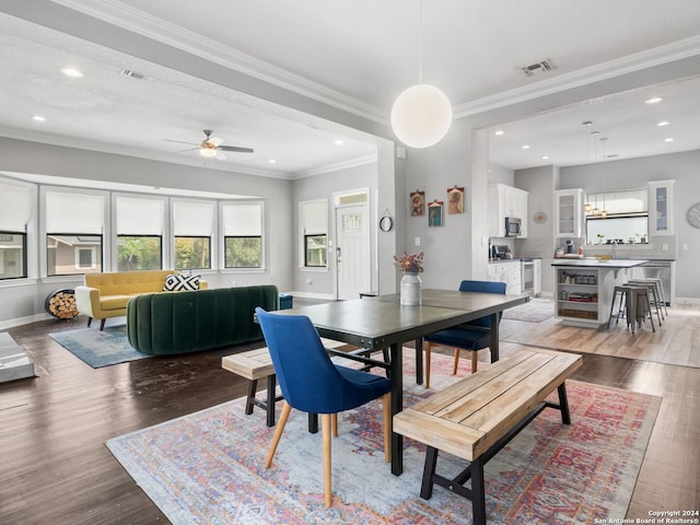 dining area featuring wood-type flooring, ornamental molding, and ceiling fan