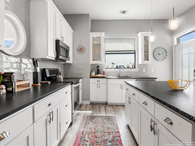 kitchen featuring white cabinets, tasteful backsplash, decorative light fixtures, hardwood / wood-style flooring, and appliances with stainless steel finishes