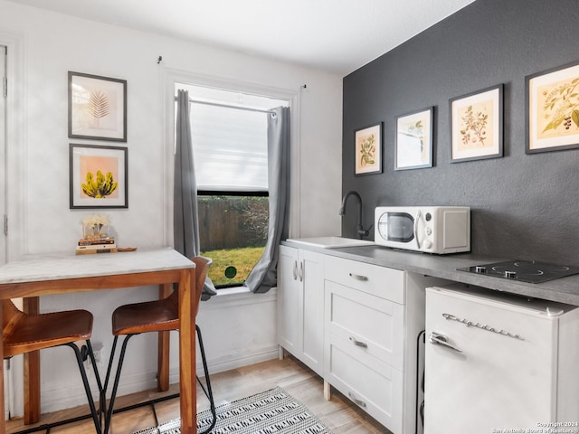 kitchen featuring white cabinets, light hardwood / wood-style flooring, sink, and white appliances