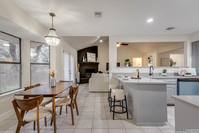 kitchen with vaulted ceiling, a wealth of natural light, hanging light fixtures, and stainless steel dishwasher