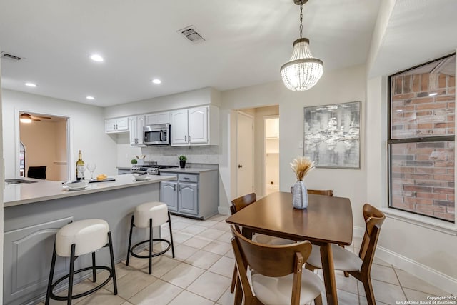 kitchen with decorative light fixtures, white cabinetry, stainless steel appliances, decorative backsplash, and light tile patterned floors