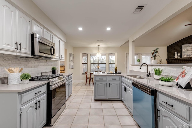 kitchen with kitchen peninsula, appliances with stainless steel finishes, sink, light tile patterned flooring, and lofted ceiling