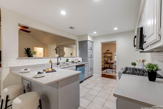 kitchen with a kitchen bar, white cabinetry, stainless steel appliances, sink, and kitchen peninsula