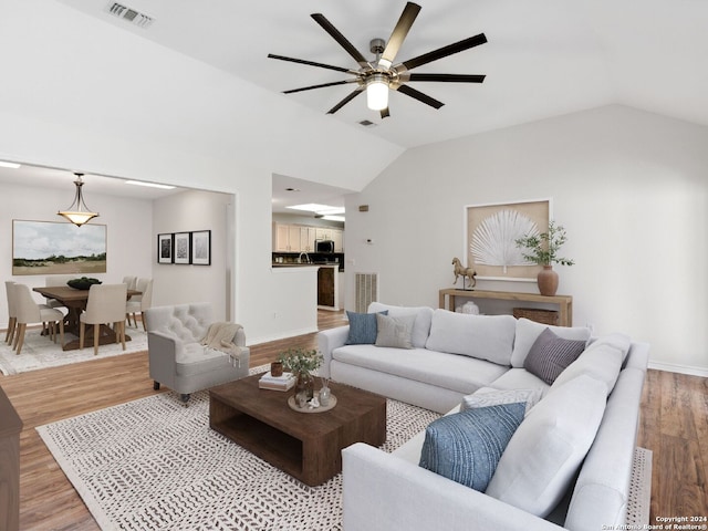 living room with ceiling fan, vaulted ceiling, and wood-type flooring