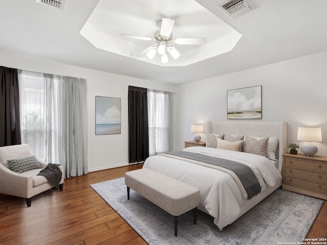 bedroom with ceiling fan, a raised ceiling, and dark hardwood / wood-style flooring