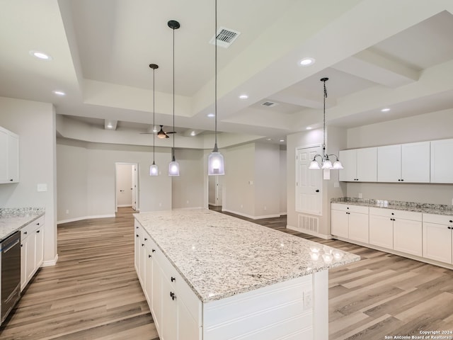 kitchen featuring light stone counters, hanging light fixtures, white cabinetry, a spacious island, and light hardwood / wood-style floors