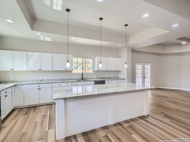 kitchen featuring light hardwood / wood-style flooring, white cabinets, decorative light fixtures, and sink