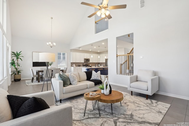 living room with ceiling fan with notable chandelier, light tile patterned floors, high vaulted ceiling, and a healthy amount of sunlight