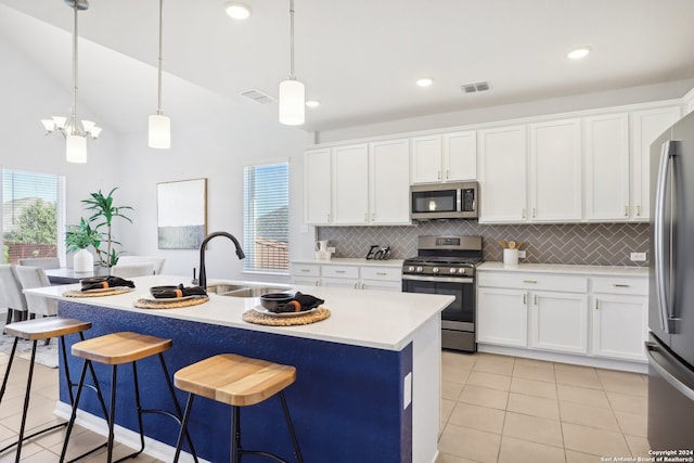 kitchen featuring pendant lighting, sink, white cabinetry, a center island with sink, and appliances with stainless steel finishes