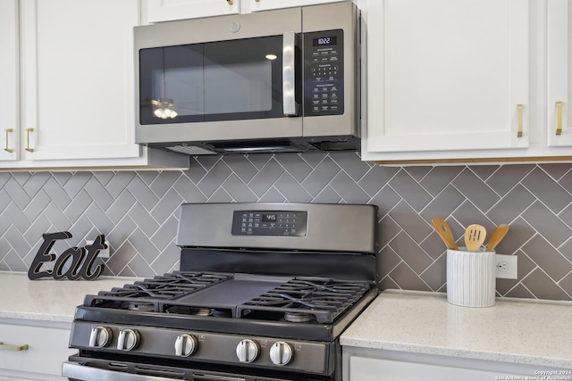 kitchen featuring light stone counters, white cabinetry, stainless steel appliances, and tasteful backsplash