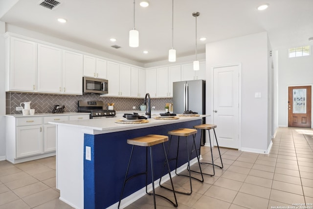 kitchen with white cabinets, a kitchen island with sink, stainless steel appliances, and pendant lighting