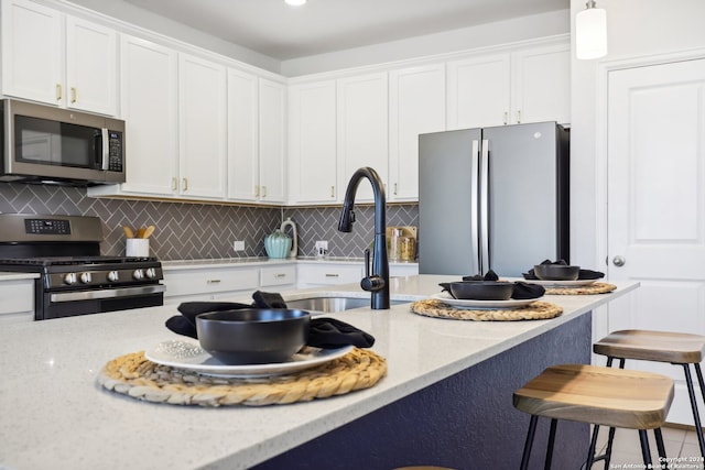 kitchen with pendant lighting, appliances with stainless steel finishes, white cabinets, and light stone countertops