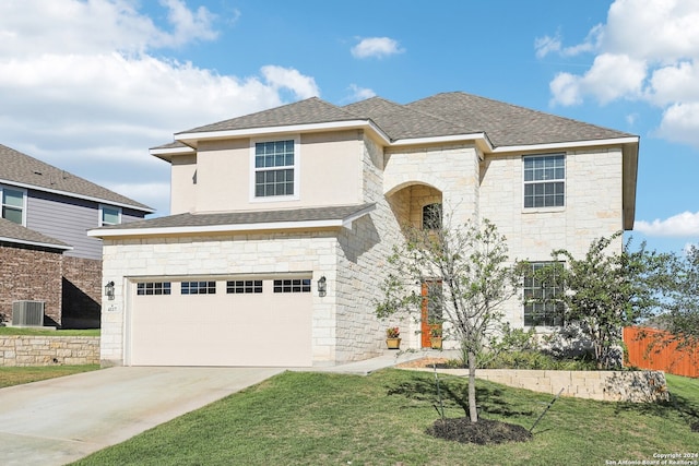 front facade featuring a front yard, a garage, and central air condition unit