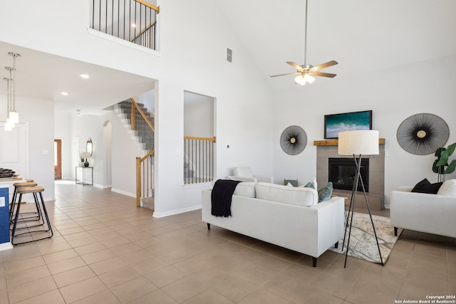 living room featuring high vaulted ceiling, ceiling fan, a tile fireplace, and light tile patterned flooring