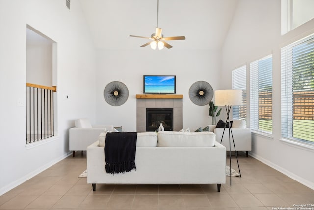 living room with ceiling fan, light tile patterned floors, high vaulted ceiling, and a tile fireplace