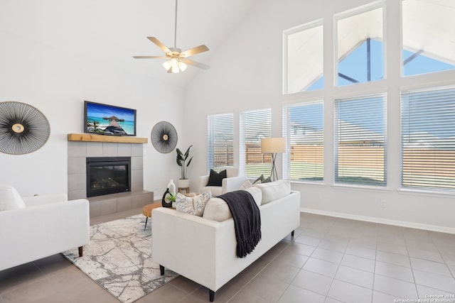 tiled living room with high vaulted ceiling, ceiling fan, and a fireplace